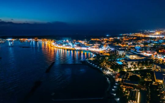 Aerial view of Paphos embankment or promenade at night with reflection of city lights in sea water. Famous Cyprus mediterranean resort.